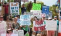 people hold signs at a protest calling for state parks to be protected, reading messages like 'Fight for nature' and 'save our parks!'