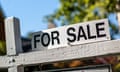 A black and white 'for sale' sign outside a house