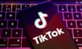 A phone displaying the TikTok logo is shown resting on a keyboard