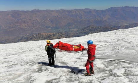 two people carry a body on a stretcher on an icy mountain