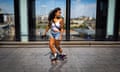 A woman wearing a white vest and denim shorts skating backwards near Westfield shopping centre in Stratford, east London