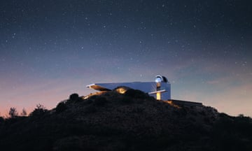 A sloping sliver building on a hilltop at sunset