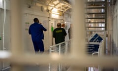 Two male prisoners walk down the landing towards to prison officers (photo by Andrew Aitchison / In pictures via Getty Images)