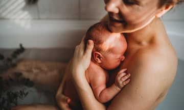 Happy smiling mother holding her newborn baby after being born in a bath