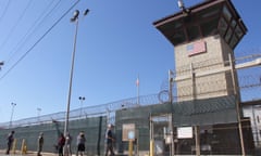 People walk past a guard tower at Guantanamo Bay, Cuba