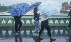 People holding up umbrellas walk across Westminster Bridge in heavy rain