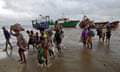 Families arrive on a beach in Mozambique carrying belongings wrapped in fabric bundles on their heads