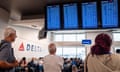 People in a packed airport terminal wait with luggage and look at flight information screens