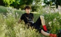 A young male model photographed outside in a meadow of flowers.