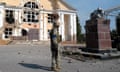 A Ukrainian soldier with damaged buildings and statue