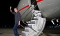 Gershkovich waves at the bottom of the steps of a silver aircraft at night