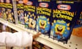 A child points to a row of cartoon-emblazoned macaroni and cheese containers.