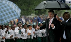 Tony Blair and then Sierra Leone president, Alhaji Tejan Kabbah, pass schoolchildren in heavy rain on a visit to a school in 2007.