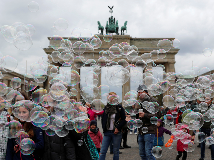 FILE PHOTO: People are seen behind soap bubbles created by a street artist (not pictured) in front of the Brandenburg Gate in Berlin, Germany, April 12, 2019.    REUTERS/Fabrizio Bensch