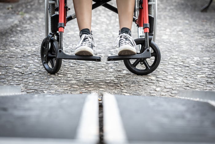 Image of a person's feet prepared to board a wheelchair ramp.