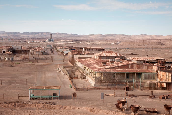 Rust-covered buildings with a desert-scape in the background