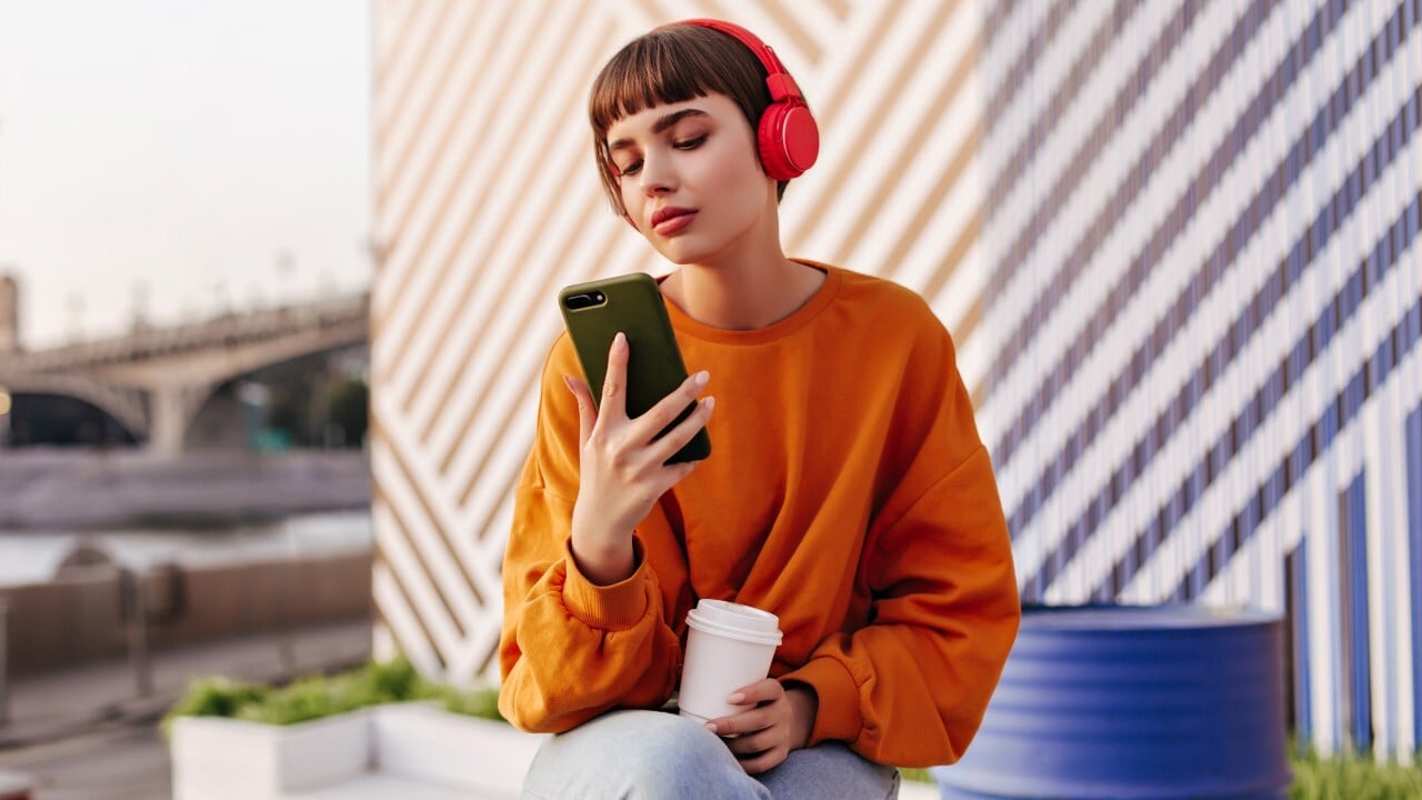 woman with headphones on looking at her phone