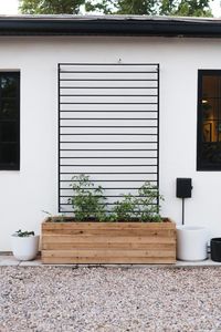 Raised Planter Box with Black Horizontal Slatted Trellis Mounted on White Wall