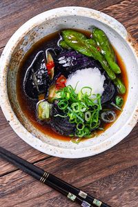 nasu no agebitashi served in a cream bowl and topped with grated daikon and chopped spring onion