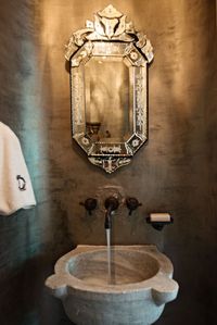 Artisan Jim Sanchez created the custom plaster walls which work beautifully with the limestone sink, another artifact that was re-purposed from an old fountain in Detroit. For a understated look, the walls were custom painted in gun metal grey. Powder room.