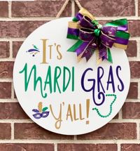 "It's Mardi Gras Time ! Let the Good Times Roll!! The perfect piece to add to your front door this Carnival season. This sign will be a big hit on your front door or porch. Also can be used on a wall inside your home, entryway or over your mantle. Door hangers also make the perfect gift for anyone that just loves Mardi Gras. Sign Size & Description - 18 inch round, made from 1/2 \" thick wood. High quality bow is attached with staples Hand painted with white chalk paint. Wording is permanent out