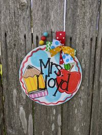 "Start school in style with this adorable personalized teacher door hanger. Perfect for any classroom and as always I'll be glad to customize this cutie for you. Hand painted on 5 mm thick circle 11\" in diameter. Wire hanger with bead and ribbon accent."