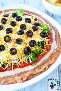 Taco dip with Refried Beans is a perfect Game Day Appetizer Dip. Dippable layers of salsa, sour cream, and Mexican Cheese - see what else!