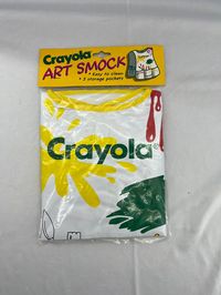 "Here we have a vintage / retro 1993 Crayola Arts & Crafts Smock By Binney & Smith, Inc.  Let's face it.  Arts and crafts projects can be messy!  Between the paint and the glitter and the markers and the glue and the clay and whatever other substance your imagination deems you need for your piece things can get carried away quickly!  Luckily the good people at Crayola recognized the worry and created adorable reusable plastic smocks to project your child's clothing from all of the messy art supplies.  This cute Crayola Art Smock  features three storage pockets as well as ties on the sides.  The smock features paint splatters in red, green, and yellow as well drawings of paint brushes, crayons, pencils, etc.  It is just too cute! It is the perfect gift for any Crayola collector. Great for a