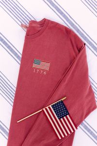 Most sizes and colors are available to ship next day! I love this USA shirt. God Bless the USA! These vintage inspired embroidered American flags are perfect for showing your patriotism this summer at your Fourth of July celebrations! Embroidered on your choice of a Comfort Colors tank, tee, long sleeve, crewneck sweatshirt, or quarter zip.