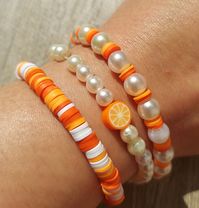 This is a unique handmade trio bracelet design made with a mix of different shades of orange and white clay beads, with pearl accent beads and accent orange clay fruit bead. The elastic band makes easy to fit most wrists. Creating this design was inspired by a young girl from the Gen-z/Gen-alpha generation that likes to wear colorful, unique and cute jewelry. It's a unisex bracelet, anyone who loves colorful, cute, and unique designs will love it!🍊