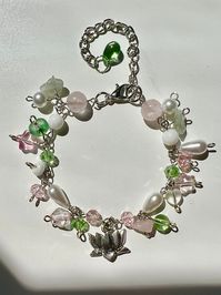 ༉. Beaded chain style bracelet with pink, green, and white beads. Mixture of glass, pearl and quartz beads with silver findings and a silver lotus charm. Beautiful touch to many different outfits. Perfect gift!! ༉. Adjustable but if you want it bigger/smaller please message me! ༉. Shipping US + Canada only ༉. Products are handmade please handle delicately, leave out of wet environments and avoid snagging ༉. Message me with any questions