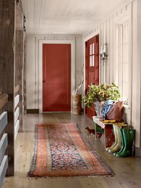 An antique runner from Budapest and a bench made by Laurie's grandfather bring a sense of history to the upstairs hallway, which overlooks the home's great room. "We chose vintage doorknobs that are grazed and nicked, and just wonderful to wrap your hand around," Laurie explains. The doors are painted Red Rock by Benjamin Moore.