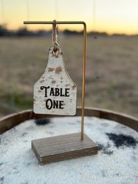 "Elevate your wedding with a touch of rustic charm with these unique cowhide table number signs.  This piece is perfect for western-themed weddings. Perfect for wedding table decor. Order yours today and make a statement with this one-of-a-kind wedding accessory! *Measures 10\" x 4.5"