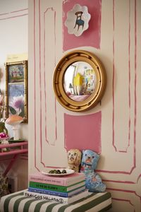 Brass rimmed mirror on hand painted wall in eclectic apartment.