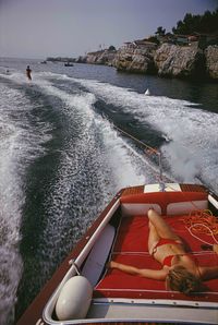 A woman sunbathing in a motorboat as it tows a waterskiier, in the sea off the Hotel du Cap-Eden-Roc in Antibes on the French Riviera, August 1969.Hand-selected from American photographer Slim Aarons' classic collection. Aarons is renowned for his evocative photographs of, as he described it, "attractive people doing attractive things in attractive places." Each image is printed from scans of the original negative then mounted on aluminum and faced with museum quality Plexiglas. Please allow app