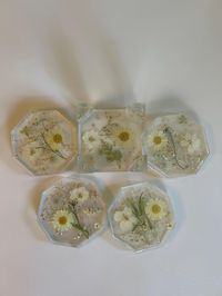 Floral daisy like coasters embedded in resin.  Set of four with holder, octagon shaped.  Dried pressed flowers with greenery add elegance to your beverage. Transparent feet on coasters and holders to prevent slipping. Great addition to your  table, bar, ir party! Handmade item.