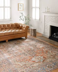 a living room with a couch, rug and fire place in it's center