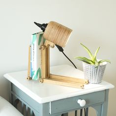 a lamp on top of a table next to a potted plant and a book