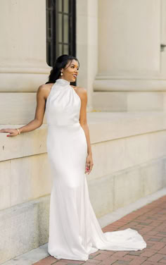 a woman in a white dress leaning against a wall