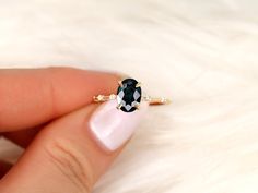 a woman's hand holding a ring with an oval shaped black diamond on it