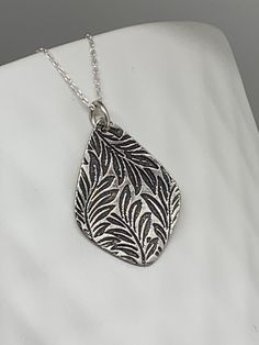 This lovely floral leaf teardrop necklace has been entirely handmade using .999 fine silver. It has been cut from fine silver precious metal clay, textured, fired and oxidized. The pendant hangs from a sterling silver diamond cut cable chain. This fine silver long teardrop shaped pendant features an embossed leafy floral textured pattern. Pendant size: approximately 1 1/8 x 3/4 inches Chain length: adjustable at 16 and 18 inches can also be customized to whatever length needed The necklace is se Hand Forged Silver Necklaces In Nature-inspired Style, Hand Forged Silver Nature-inspired Necklace, Hand-forged Silver Nature-inspired Necklace, Silver Etched Necklace With Flower Pendant, Silver Etched Nature-inspired Necklaces, Nature-inspired Silver Etched Necklaces, Handmade Leaf-shaped Sterling Silver Jewelry, Handmade Sterling Silver Leaf-shaped Jewelry, Silver Engraved Nature-inspired Necklace