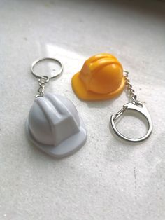 two key chains and a hard hat on a white counter top, one with a yellow plastic cap