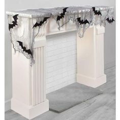 a white fireplace with bats on the mantle and curtains hanging from it's sides