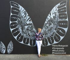 a woman standing in front of a butterfly mural