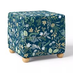 a blue and green floral ottoman with wooden legs