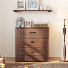 a wooden dresser sitting in a living room next to a lamp and pictures on the wall