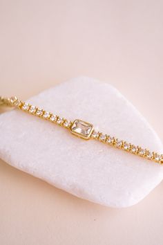 Meet your new favorite accessory: the Amelia Brilliant Cut Tennis Bracelet! We love how it effortlessly adds sparkle to your everyday look, whether you're dressing up for a date night or just want to feel a bit more glam. With its row of dazzling stones and eye-catching emerald cut center, all set in delicate 14k gold plating, this bracelet makes every outfit feel a little more special. The perfect blend of chic and sophisticated, the Amelia Bracelet lets you shine in your own unique way.BRACELE Elegant Cubic Zirconia Diamond Bracelet With Bling, Adjustable Cubic Zirconia Diamond Bracelet For Party, Party Adjustable Diamond Bracelet In Cubic Zirconia, Adjustable Party Diamond Bracelet In Cubic Zirconia, Party Adjustable Cubic Zirconia Diamond Bracelet, Adjustable Cubic Zirconia Chain Bracelet For Party, Glamorous Adjustable Bracelet As Gift, Party Diamond Bracelet With Adjustable Chain, Glamorous Diamond Bracelet For Gift