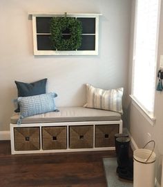 a white bench with baskets underneath it and a wreath hanging on the wall behind it