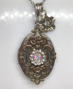 This stunning vintage inspired photo locket is a true treasure that captures the essence of old-world charm. Adorned with delicate rhinestones and bronze/silver charm, this antique inspired photo locket exudes timeless elegance and sophistication. It doubles as a beautiful bridal necklace, making it the perfect accessory for any bride on her special day. Whether you're looking for a thoughtful birthday present or a romantic gift for your wife, this exquisite locket is sure to be cherished for ye Wedding Locket Necklace In Metal, Wedding Metal Locket Necklace, Elegant Antique Finish Round Locket Necklace, Elegant Antique Finish Round Pendant Locket Necklace, Elegant Bronze Locket Necklace For Wedding, Antique Jeweled Jewelry For Anniversary, Antique Silver Necklace With Vintage Charm For Anniversary, Elegant Pendant Locket Necklace With Antique Finish, Antique Silver Medallion Locket Necklace With Vintage Charm