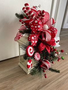 a red and white christmas tree with candy canes, ornaments and greenery on it